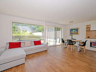 Experience modern living in this spacious open-plan apartment, featuring a comfortable L-shaped sofa and a dining area perfect for entertaining.