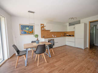 Discover modern living in this bright and airy open-concept space, featuring a sleek white kitchen with ample cabinet space and a charming dining area.