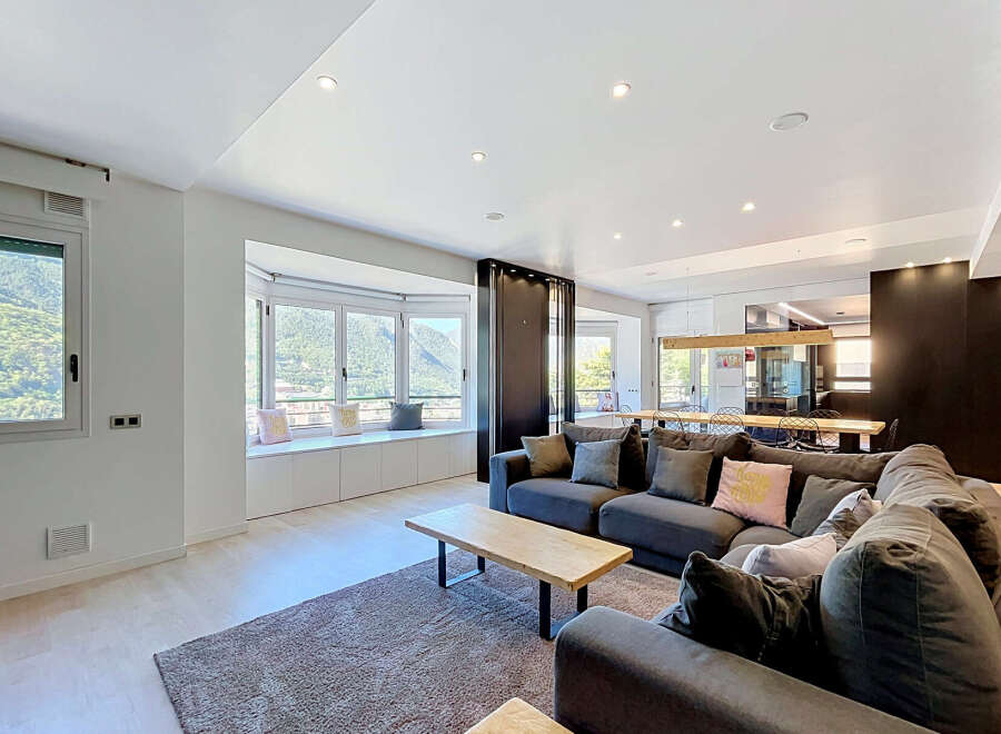 Experience modern living in this spacious open-plan apartment, featuring a large sectional sofa and a stylish dining area.