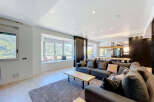 Experience modern living in this spacious open-plan apartment, featuring a large sectional sofa and a stylish dining area.