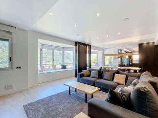 Experience modern living in this spacious open-plan apartment, featuring a large sectional sofa and a stylish dining area.