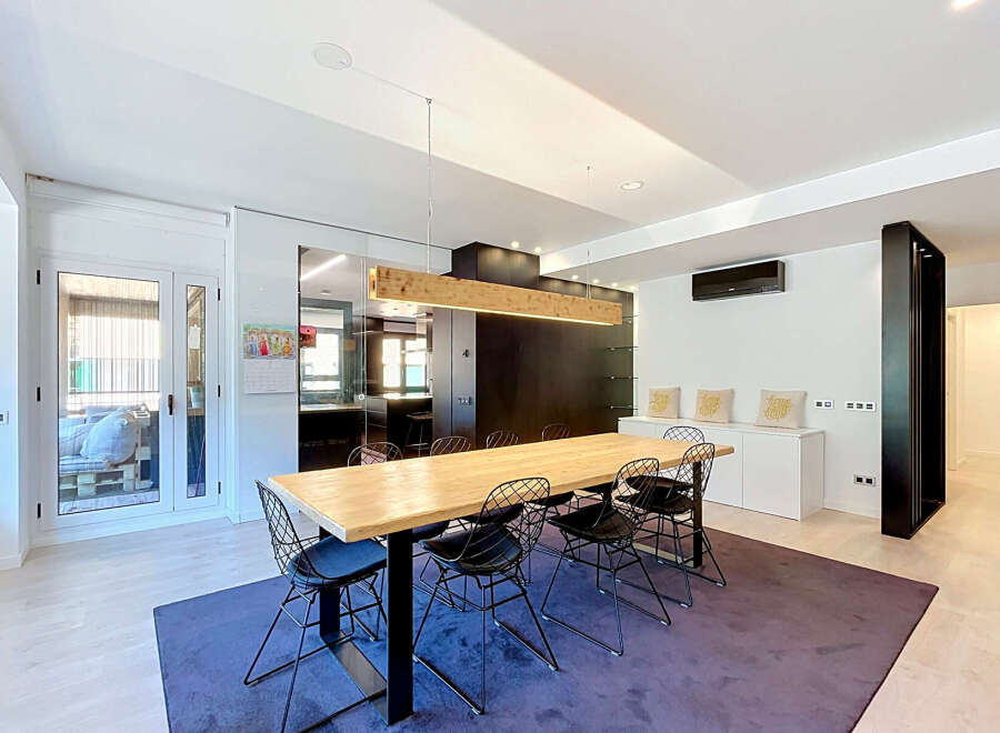 Experience modern living in this spacious dining area, featuring a large wooden table with contemporary wire chairs perfect for gatherings.
