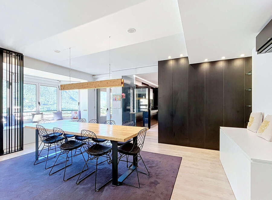 Experience modern living in this spacious dining area, featuring a large wooden table with contemporary wire chairs perfect for family gatherings.