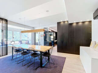 Experience modern living in this spacious dining area, featuring a large wooden table with contemporary wire chairs perfect for family gatherings.