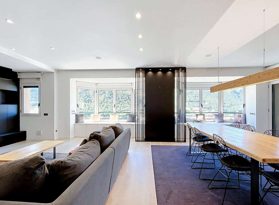 Experience modern living in this spacious open-plan apartment, featuring a comfortable living area with a large sectional sofa and a sleek coffee table.