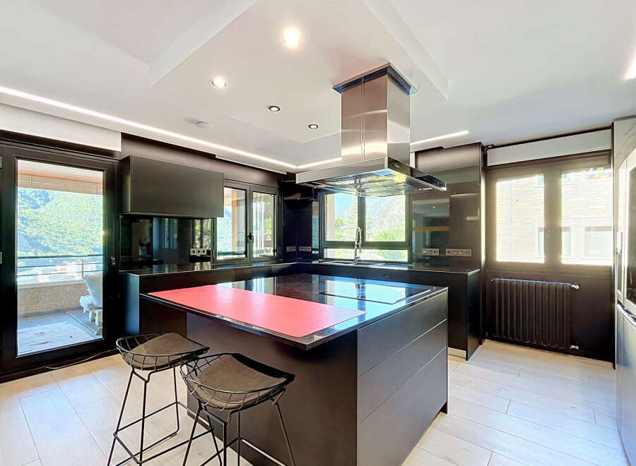 Experience modern luxury in this sleek, contemporary kitchen featuring a spacious island with a vibrant red countertop, perfect for meal prep and casual dining.