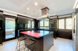 Experience modern luxury in this sleek, contemporary kitchen featuring a spacious island with a vibrant red countertop, perfect for meal prep and casual dining.