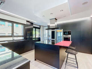 Experience modern luxury in this sleek, black kitchen featuring a spacious island with a vibrant red countertop, perfect for entertaining.