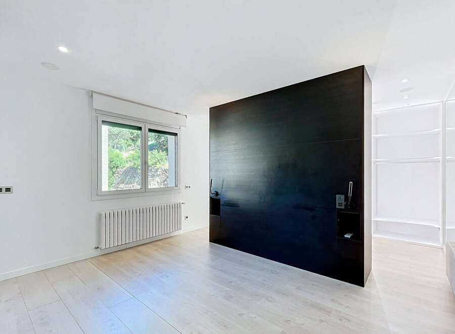 Discover modern living in this spacious room featuring a striking dark wood feature wall and a large window offering natural light.