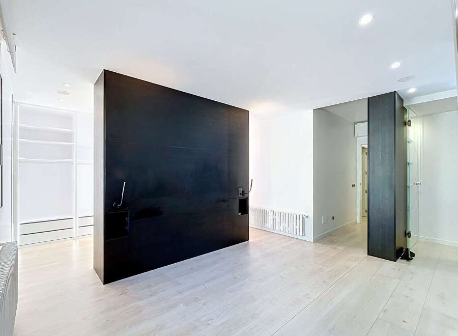 Experience modern living in this spacious room featuring a striking black headboard wall and sleek, minimalist design.