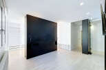 Experience modern living in this spacious room featuring a striking black headboard wall and sleek, minimalist design.