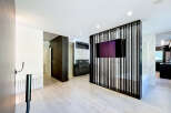 Experience modern luxury in this open-concept living space, featuring a sleek black slatted room divider with an integrated TV.