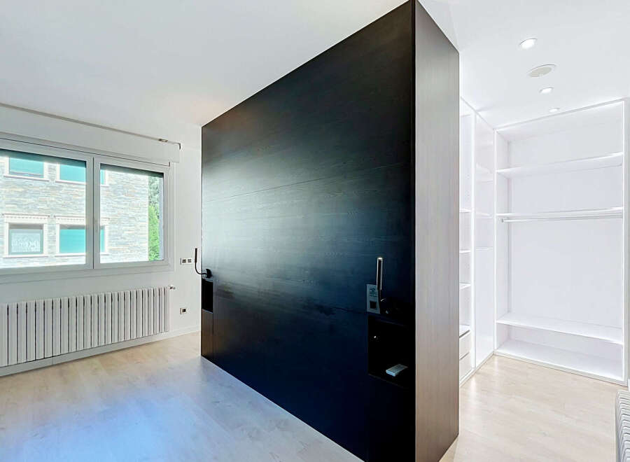 Discover modern living in this spacious bedroom featuring a striking dark wood statement wall that adds a touch of sophistication.