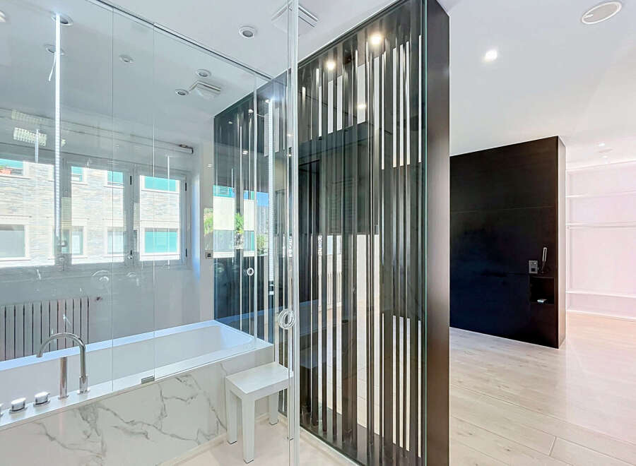 Experience modern luxury in this stunning bathroom featuring a sleek bathtub with marble accents and a contemporary faucet.