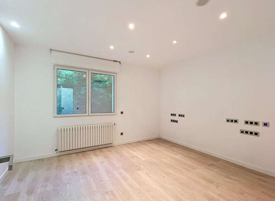Discover this modern, empty room featuring a large window overlooking lush greenery, perfect for natural light.