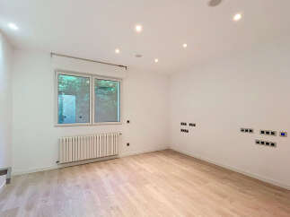Discover this modern, empty room featuring a large window overlooking lush greenery, perfect for natural light.