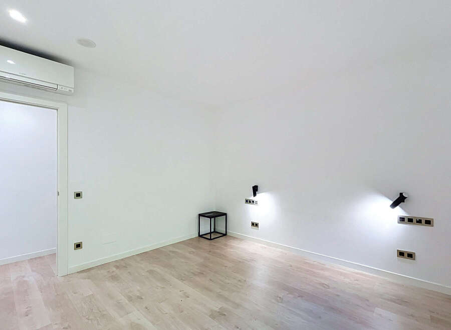 Experience modern living in this bright and airy room, featuring a sleek air conditioning unit and elegant wooden flooring.
