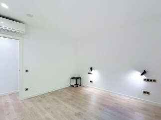 Experience modern living in this bright and airy room, featuring a sleek air conditioning unit and elegant wooden flooring.