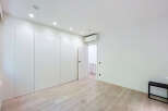 Discover this modern bedroom featuring a sleek, floor-to-ceiling white wardrobe providing ample storage.