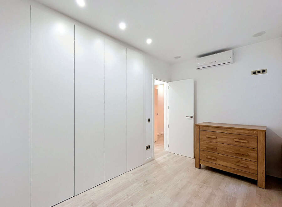 Experience modern living in this beautifully appointed bedroom featuring sleek, floor-to-ceiling white wardrobes for ample storage.