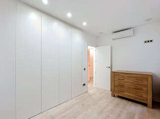 Experience modern living in this beautifully appointed bedroom featuring sleek, floor-to-ceiling white wardrobes for ample storage.