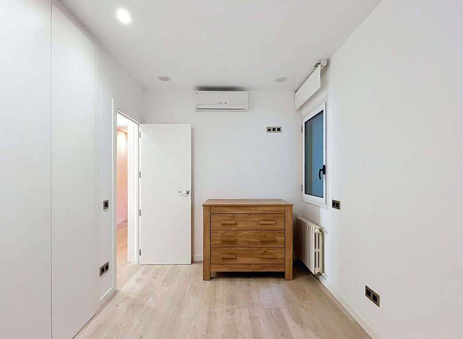 Discover this bright and modern bedroom featuring a sleek white wardrobe and a charming wooden dresser.