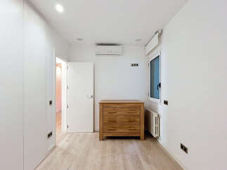 Discover this bright and modern bedroom featuring a sleek white wardrobe and a charming wooden dresser.