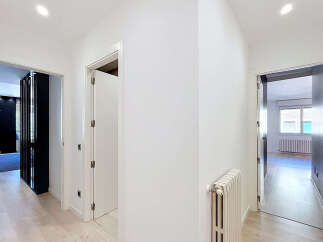 Step into this bright and airy hallway, featuring pristine white walls and elegant light wood flooring.