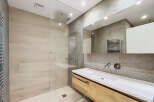 Experience modern luxury in this stunning bathroom featuring a spacious walk-in shower with a rainfall showerhead and elegant wood-look tiles.