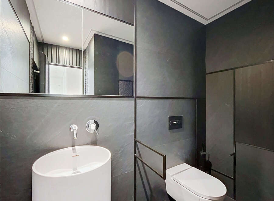 Experience modern luxury in this sleek bathroom featuring a striking white vessel sink and a minimalist wall-mounted faucet.