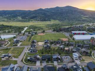 Experience luxury mountain living in this stunning aerial view of a residential community nestled against a backdrop of majestic mountains.