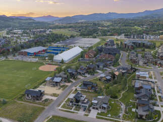 Discover luxurious mountain living in this stunning aerial view of a modern residential community nestled against a backdrop of rolling hills and majestic mountains.