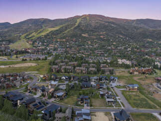 Experience luxury mountain living in this stunning aerial view of a residential community nestled at the base of a ski resort.