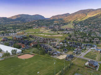 Experience luxury mountain living in this stunning aerial view of a vibrant community nestled against majestic peaks.
