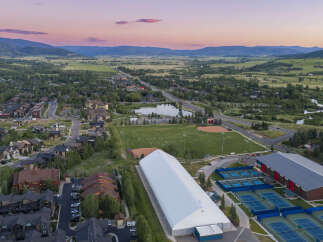 Discover this stunning property featuring a large indoor sports facility, multiple outdoor tennis courts, and a baseball field, perfect for athletes and recreation enthusiasts.