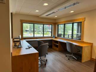 Experience a productive workspace with this beautifully designed office area, featuring a spacious L-shaped wooden desk that maximizes natural light from large windows.