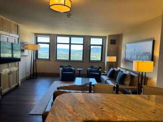 Experience breathtaking mountain views from this stunning living room, featuring a comfortable leather sofa and two accent chairs perfect for relaxation.