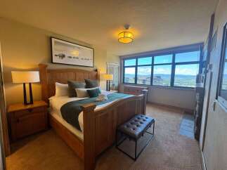 Experience breathtaking views from this luxurious bedroom, featuring a spacious king-size bed and elegant wooden furniture.