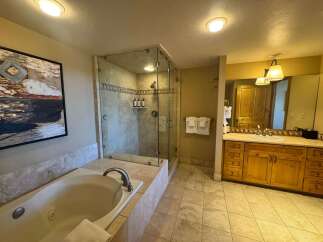 Indulge in luxury with this spacious bathroom featuring a deep soaking tub and a separate glass-enclosed shower.