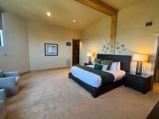 Experience ultimate comfort in this spacious bedroom, featuring a king-size bed adorned with plush pillows and a rich green duvet.