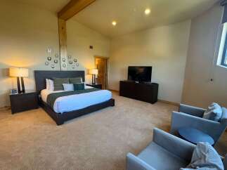 Experience ultimate comfort in this spacious bedroom, featuring a king-sized bed with plush linens and decorative pillows.