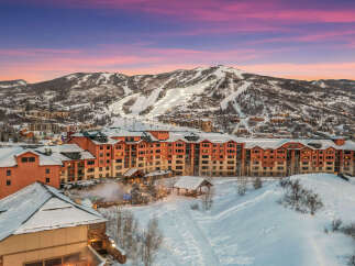 Experience luxury mountain living in this stunning ski resort property, boasting panoramic views of snow-capped peaks and vibrant sunset skies.