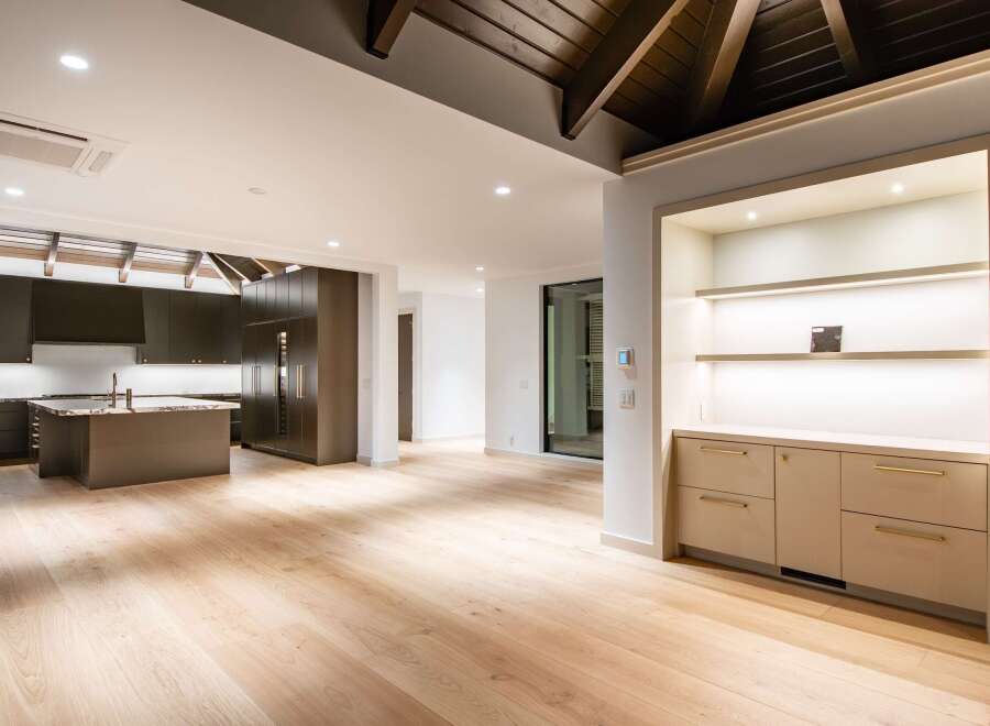 Experience modern luxury in this spacious open-concept living area, featuring a sleek dark wood kitchen with a central island and marble countertops.