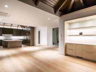 Experience modern luxury in this spacious open-concept living area, featuring a sleek dark wood kitchen with a central island and marble countertops.