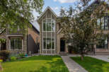 This charming home features a striking facade with a mix of stone and stucco finishes, complemented by a large arched window on the upper level.