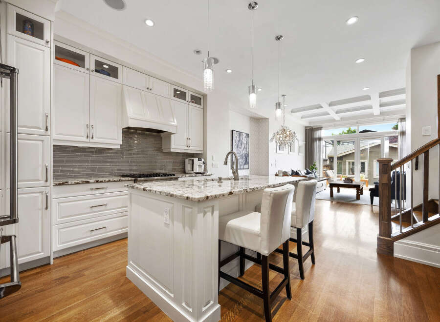 Experience luxury living in this stunning modern kitchen, featuring sleek white cabinetry, granite countertops, and a spacious island perfect for entertaining.