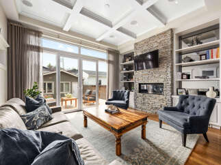 Experience luxury living in this stunning living room featuring a floor-to-ceiling stone fireplace and a large entertainment system.