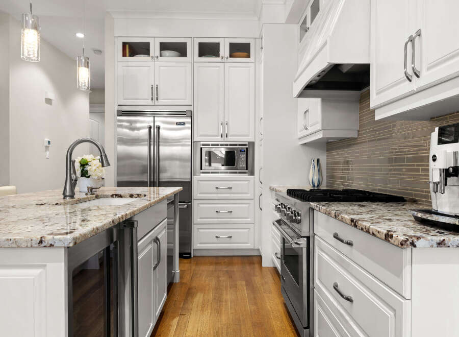 Experience luxury in this stunning kitchen, featuring a spacious island with a granite countertop and a sleek undermount sink.