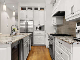 Experience luxury in this stunning kitchen, featuring a spacious island with a granite countertop and a sleek undermount sink.