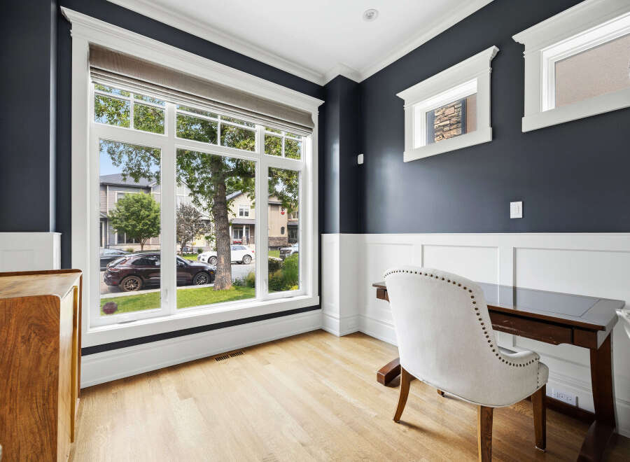 This home office features a large picture window offering views of the neighborhood and mature trees.
